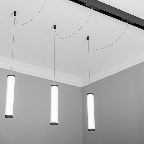 Three modern cylindrical pendant lights hanging from a black track lighting system.